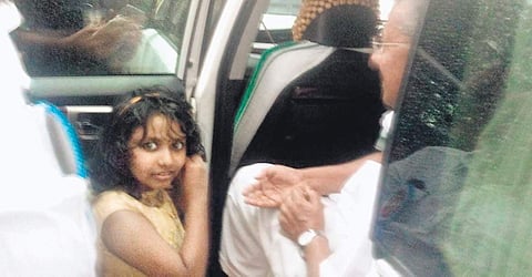 Liyana removing her earrings before handing them over to Chief Minister Pinarayi Vijayan, who is sitting in the car