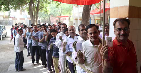Voters show their voting identity cards as they wait in queues. (Shekhar Yadav | EPS)