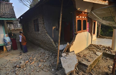 Residents talk near a house damaged in an earthquake in Mandalawangi, Banten province, Indonesia, Saturday, Aug. 3, 2019. Indonesian authorities say more 100 houses are damaged after the earthquake hit off Java island on Friday night, swaying buildings as