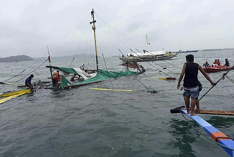 Rescuers stand beside the remains of the M/B Chichi ferry boat after it capsized due to bad weather in the waters between Guimaras and Iloilo provinces (Photo | AP)