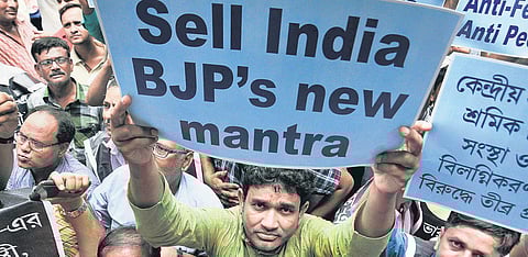 Members of Indian National Trinamool Trade Union Congress hold placards during their protest in Kolkata. (Photo | PTI)