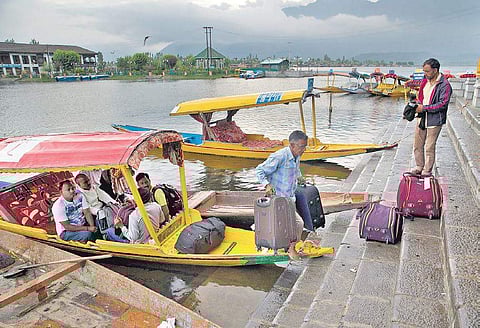 Tourists lug their bags and suitcases as they leave Srinagar. (Photo | AP)