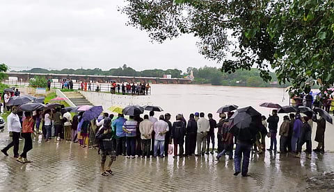 A view of people taking a look at the overflowing Tunga river near Korpaliaha choultry on Kote road in Shivamogga on Tuesday. (Photo | Shimoga Nandan, EPS)