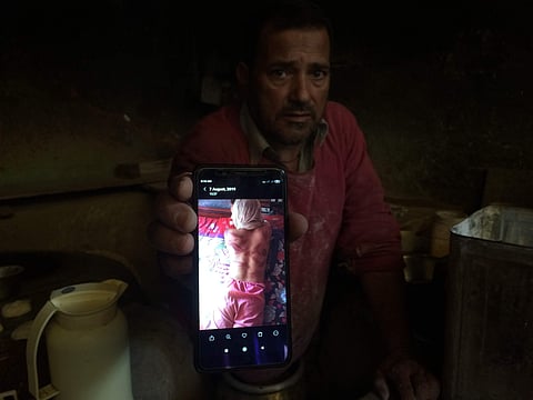Kashmiri baker Sonaullah Sofi displays a photograph of his son after he was allegedly tortured by Indian army soldiers. (Photo | AP)