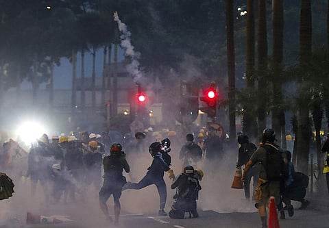 A protester throws a tear gas canister fired by riot policemen during the anti-extradition bill protest in Hong Kong. (Photo | AP)