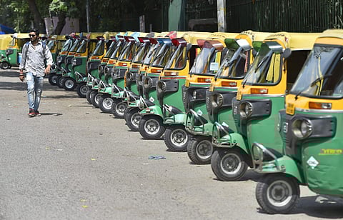 A man walks in front of auto-rickshaws seen parked along a road, during transport strike in New Delhi. (Photo | PTI)