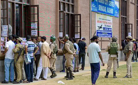 Security personnel stand guard as local people buy air-tickets from a special ticket counters set up by the government on the 29th day of restrictions after abrogration of the provisions of Article of 370 in Srinagar Monday September 2 2019. | PTI