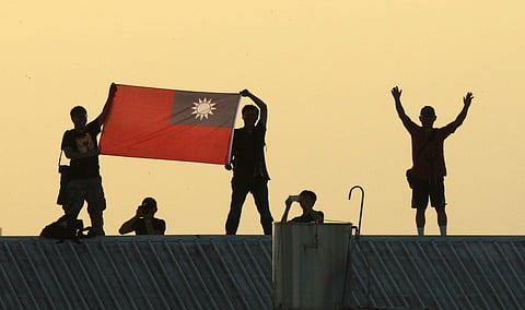 Locals on a warehouse rooftop display the national flag while watching Taiwan fighter jets practice during military exercises in Chiayi, central Taiwan (File photo| AP)