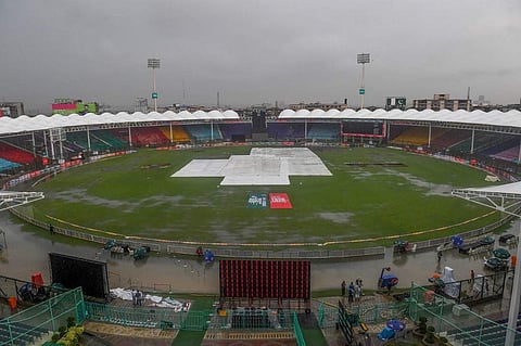 Covers are laid out on the pitch during heavy monsoon rain at the National Cricket Stadium in Karachi. (Photo | AFP)