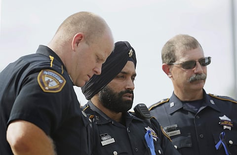 In this Aug. 30, 2015, photo, Harris County Sheriff's Deputy Sandeep Dhaliwal, center, grieves with Deputies Dixon, left, and Seibert, right, at a memorial for Deputy Darren Goforth, at the Chevron where he was killed, in Houston. (Photo | AP)