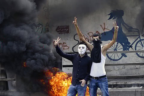 Anti-government protesters make victory signs next to tires that were set on fire to block a road during a demonstration, in Beirut, Lebanon. (Photo | AP)