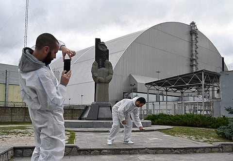 Tourists take pictures at New Safe Confinement (NSC), new metal dome encasing the destroyed reactor, at Chernobyl plant, Ukraine. (Photo | AFP)