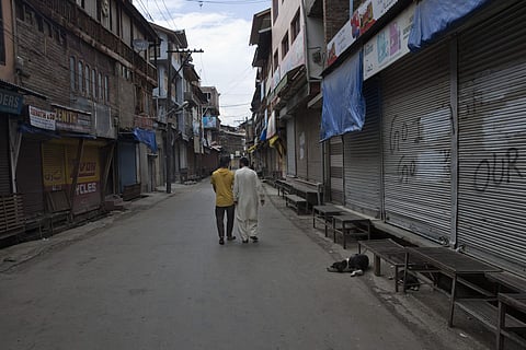 Kashmiri men walk past closed shops in central Srinagar. (Photo | AP)