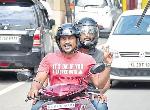 A two-wheeler rider shows the victory sign upon seeing the camera at Ambujavilasam Road B P Deepu