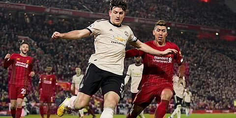 Manchester United's Harry Maguire and Liverpool's Roberto Firmino, right, challenge for the ball during the English Premier League soccer match between Liverpool and Manchester United at Anfield Stadium in Liverpool. (Photo | AP)