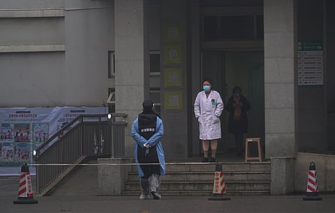Hospital staff stand outside the emergency entrance of Wuhan Medical Treatment Center, where some infected with a new virus are being treated, in Wuhan, China, Wednesday, Jan. 22, 2020. (AP Photo/Dake Kang)