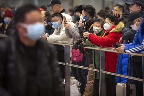 People wear face masks as they wait for arriving passengers at Beijing Capital International Airport on Thursday. (Photo | AP)