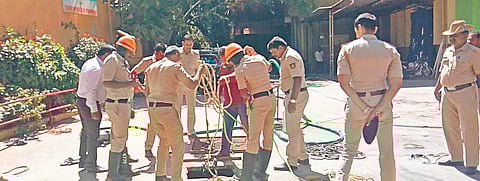 Policemen inspecting the septic tank in Shivajinagar which Siddanna and another worker were hired to clean. Manual cleaning of septic tanks without safety gear is banned by the law | MEGHANA SASTRY