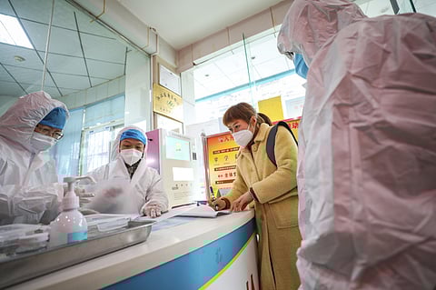 Medical workers in protective gear talk with a woman suspected of being ill with a coronavirus at a community health station in Wuhan in central China's Hubei Province, Monday, Jan. 27, 2020. (Photo | AP)