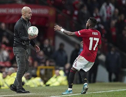 Manchester City's manager Pep Guardiola holds the ball out as United's Fred goes to collect for a throw in. (Photo | AP)