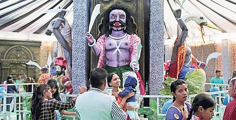 Visitors at Dhanu Yatra clicking pictures and selfies in front of the tableaux of Asuras. (Photo | EPS)