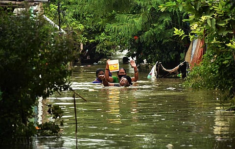 People wade through waist-deep water carrying household items at Ranigari Thota in Vijayawada. (Photo | Prasant Madugula, EPS)