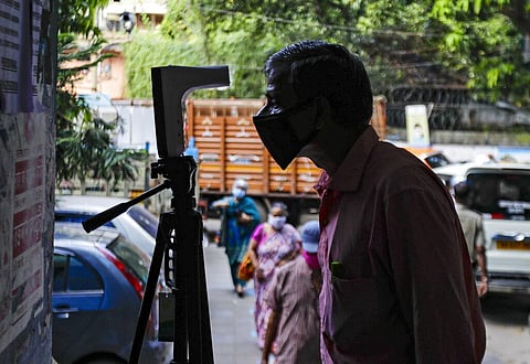 A man checks his body temparature on a device installed at the entrance of a government office, set up as a precautionary measure to check the spread of the coronavirus in Kolkata, India. (Photo | AP)