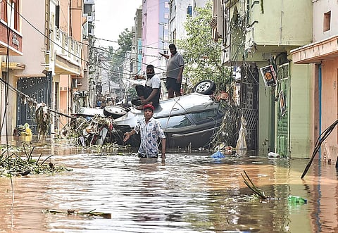 Residents navigate around an overturned car at Hafeez Baba Nagar as the area was inundated after heavy rains on Saturday |Vinay Madupu