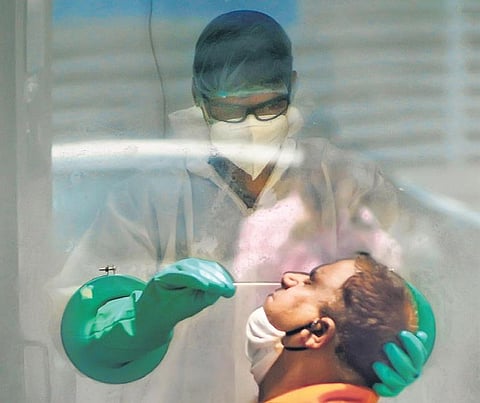 A medic collects swab sample of a suspected Covid patient for test. | Pti