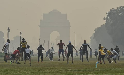 Fitness enthusiasts exercise in the lawns of India Gate amid hazy weather conditions in New Delhi Monday Oct. 26 2020. (Photo | PTI)