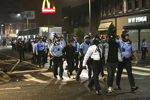 Police lead several people in handcuffs to a police van on 52nd Street in West Philadelphia in the early hours of Tuesday, Oct. 27, 2020. (Photo | AP)
