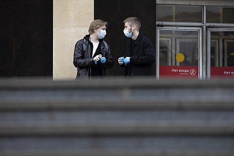 Two men wearing face masks to help curb the spread of the coronavirus talk to each other as they leave a subway in Moscow. (Photo | AP)
