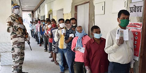 People stand in a queue to cast their votes during the first phase of Bihar Assembly polls amid the ongoing coronavirus pandemic in Gaya. (Photo | PTI)