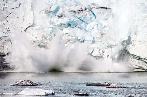 An iceberg calving with a mass of ice breaking away from the Apusiajik glacier, near Kulusuk.