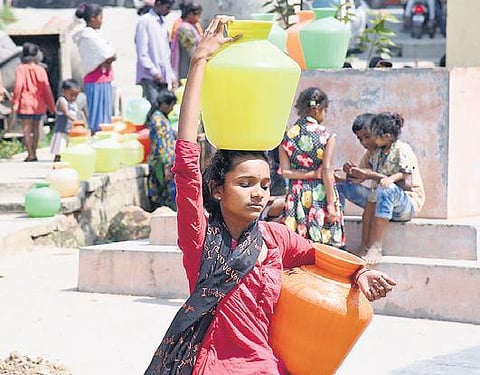 A woman from a slum in RR Nagar collects water for her household chores I NAGARAJA GADEKAL