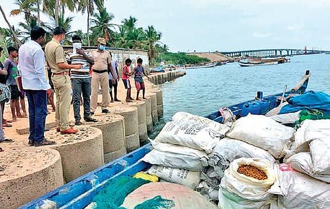 Mandapam marine police are seen with turmeric bags that were seized in a country boat stalled at Pamban recently | Express