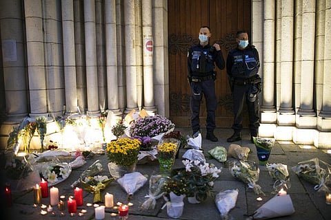 Police stand next to flowers and candles set on the steps of the Notre Dame church in Nice, France, Friday, Oct. 30, 2020. (Photo | AP)