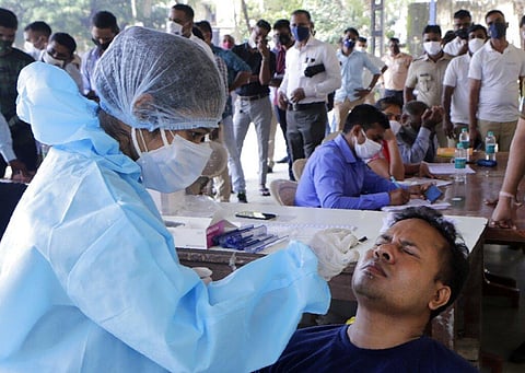 A health worker takes a nasal swab sample at a testing camp for COVID-19. (Photo | AP)
