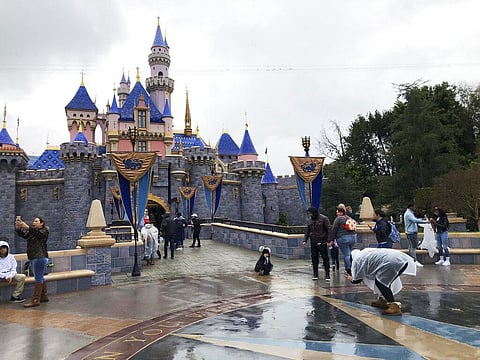 In this March 13, 2020 file photo, visitors take photos at Disneyland in Anaheim, Calif., the last day the park was open due to the COVID-19 pandemic. (Photo | AP)