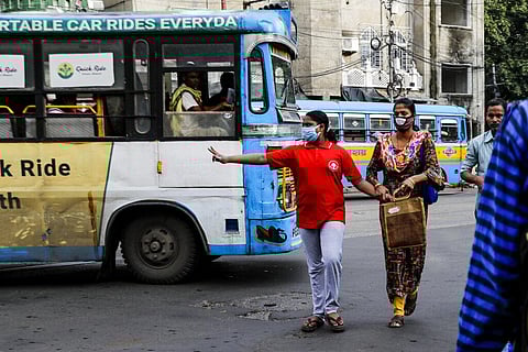 An Indian girl wearing face mask to prevent spreading coronavirus gestures towards speeding vehicles as she crosses a busy road with others in Kolkata, India, Monday, Oct. 5, 2020. (Photo | AP)