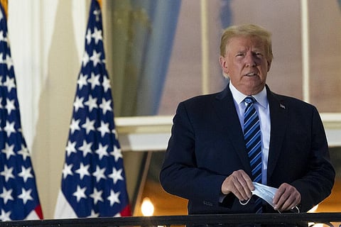 President Donald Trump holds his face mask as he stands on the Blue Room Balcony upon returning to the White House Monday, Oct. 5, 2020, in Washington. (Photo | AP)