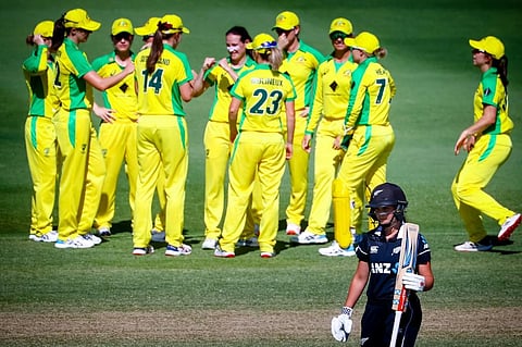 New Zealand batswoman Jess Kerr walks back to the pavilion as Australian players celebrate her dismissal. (Photo | AFP)