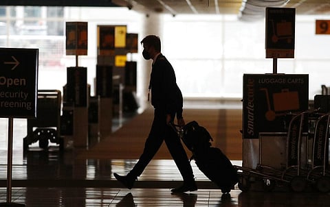 A lone airline crew member pulls his bags behind him as he walks through the baggage-claim area at Denver International Airport. (Photo | AP)