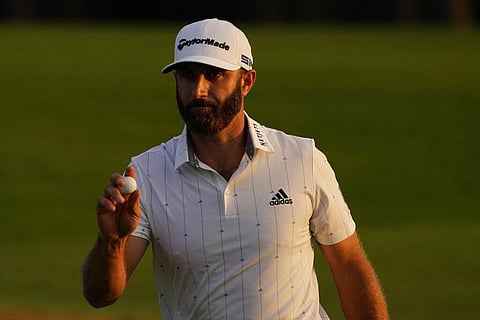 Dustin Johnson holds up his ball on the 18th green after his third round of the Masters golf tournament Saturday (Photo | AP)