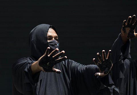 A demonstrator shows his hands covered with mock oil during a protest outside the state-owned development bank in Rio. (AP)