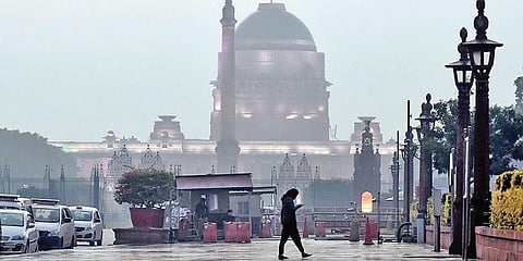 A pedestrian walks in the rain near North Block in New Delhi. (Photo | Praveen Negi, EPS)