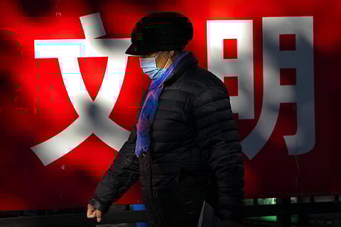 A woman wearing a face mask to protect against the coronavirus walks past a propaganda billboard with the characters for 'culture' in Beijing, Friday, Nov. 20, 2020. (Photo | AP)