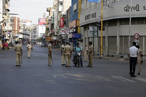 Indian policemen stop a commuter to check his identity during curfew as a precautionary measure against COVID-19 in Ahmedabad, India, Saturday, Nov. 21, 2020. (Photo | AP)