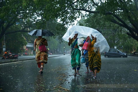 Women take shelter under plastic sheets as heavy rains lash Chennai. (Photo | Sunish P Surendran, EPS)