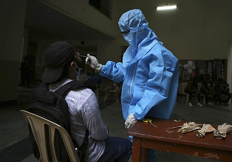 A health worker takes a nasal swab sample from a student to be tested for COVID-19. (Photo | AP)